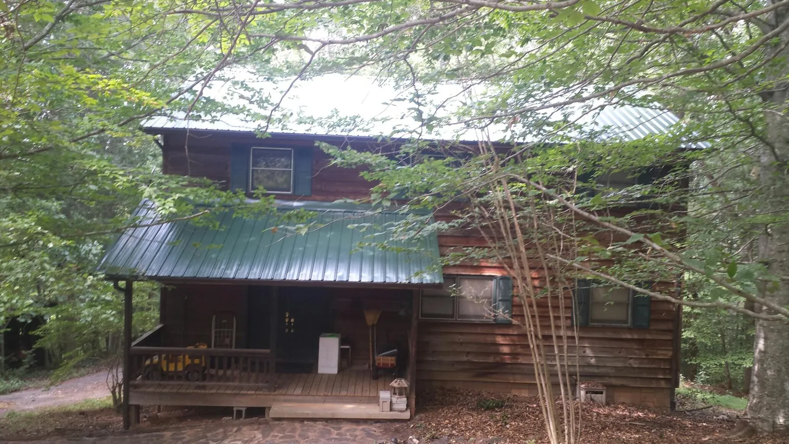 Green metal roof and covered porch on a log cabin in San Martin