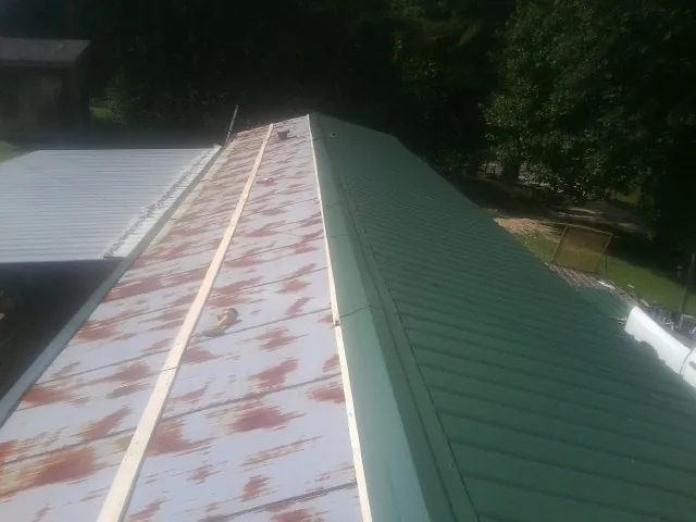 Old rusted panels beside newly installed green metal roofing — Wind Damage Roof Repair by Roofing Brothers in San Martin