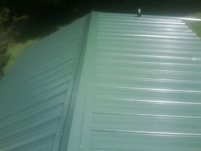 New green metal panels meeting at the ridge of a roof — Flat Roof Repair work by our crew in San Martin