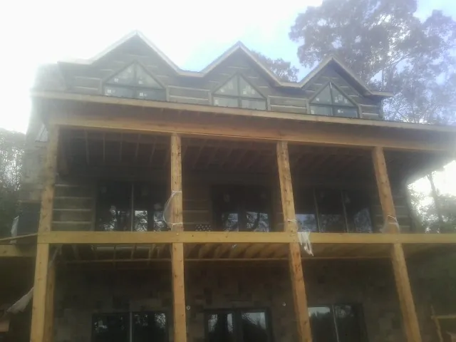 Dormers and porch framing on a large log home under construction — Roof Coating work by our crew in San Martin