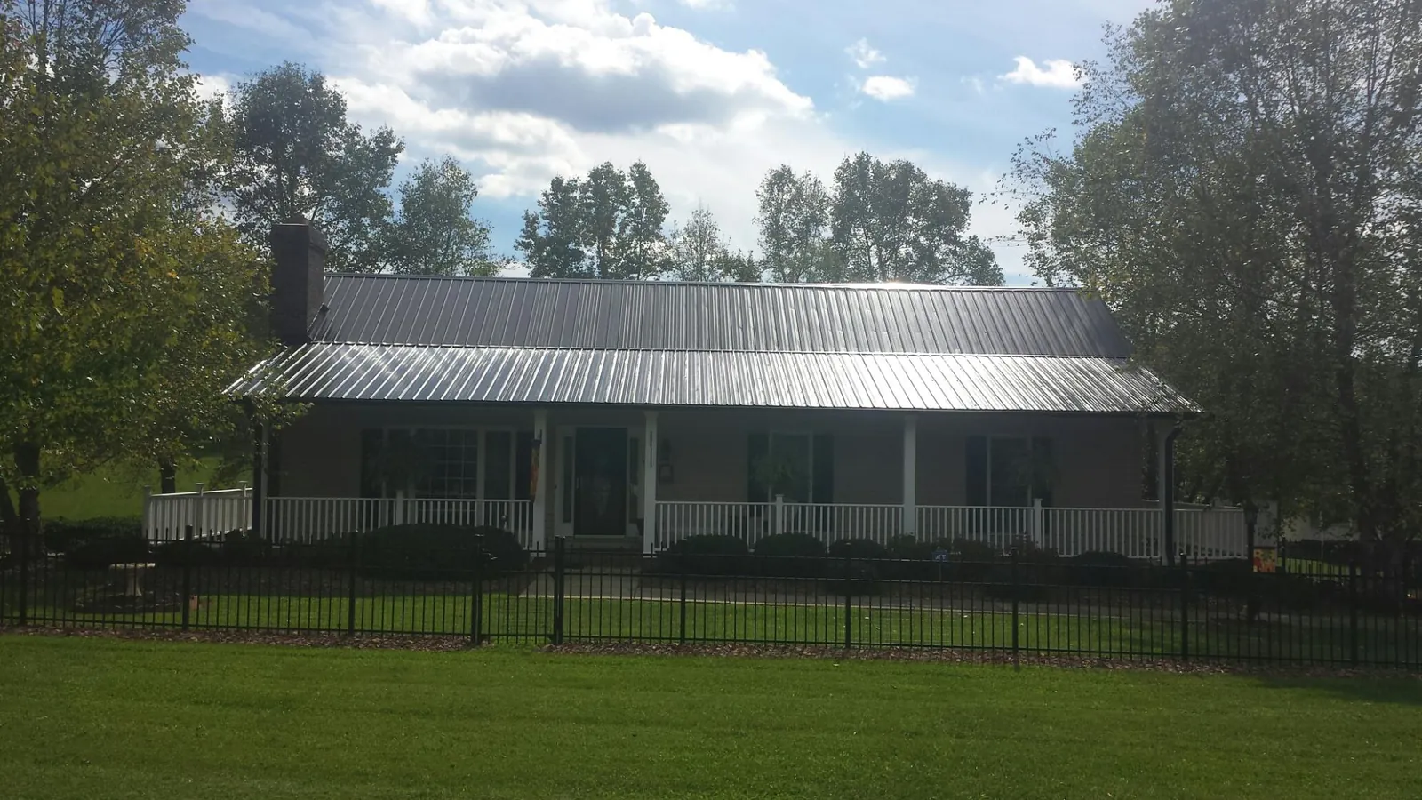 Gray metal roof on a brick ranch with a full width front porch — Gutter Guard Installation work by our crew in San Martin