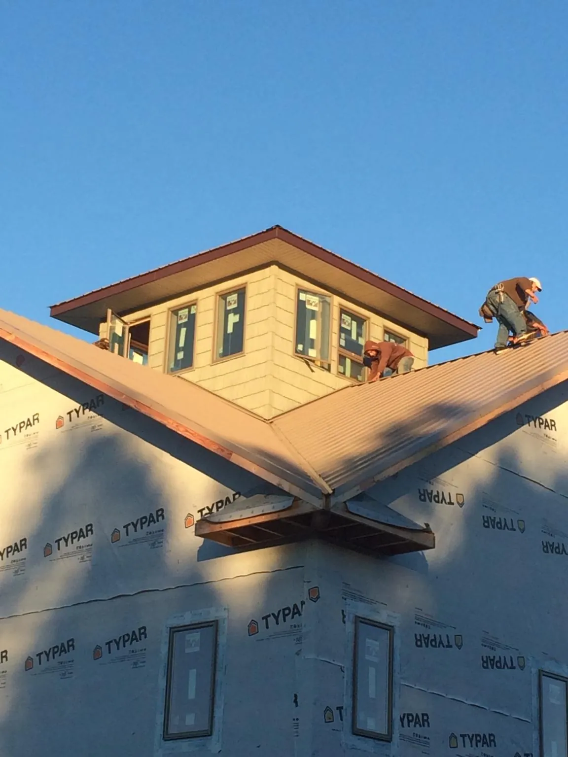 Roofers working around a rooftop cupola on a new metal roof at sunset — Roof Waterproofing in San Martin by Roofing Brothers